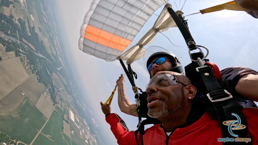 tandem skydiving pair under parachute at 5,000 feet