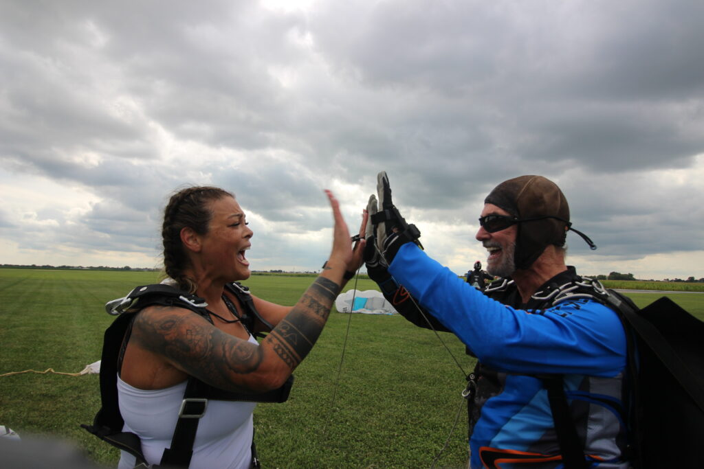 Tandem jump student high fiving their instructor after their skydive at Skydive Chicago