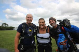 tandem students posing - 1 with hair in braids, the other with a beard - post skydive