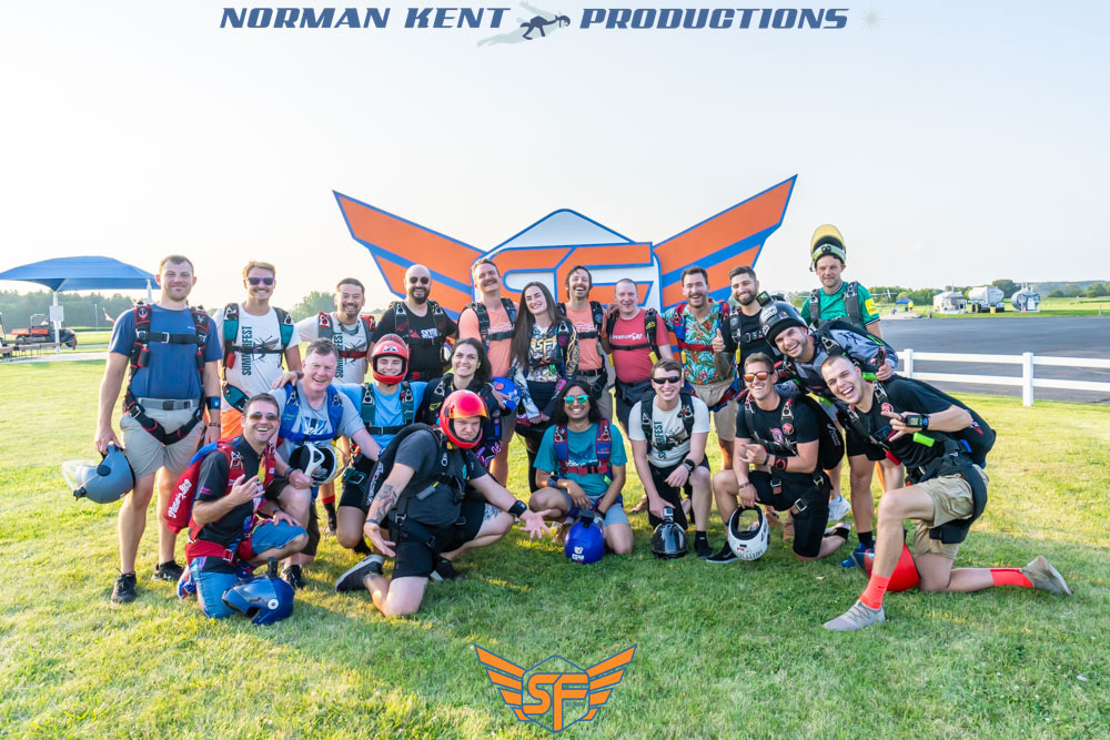 SDC Summerfest participants pose in front of the logo at Skydive Chicago