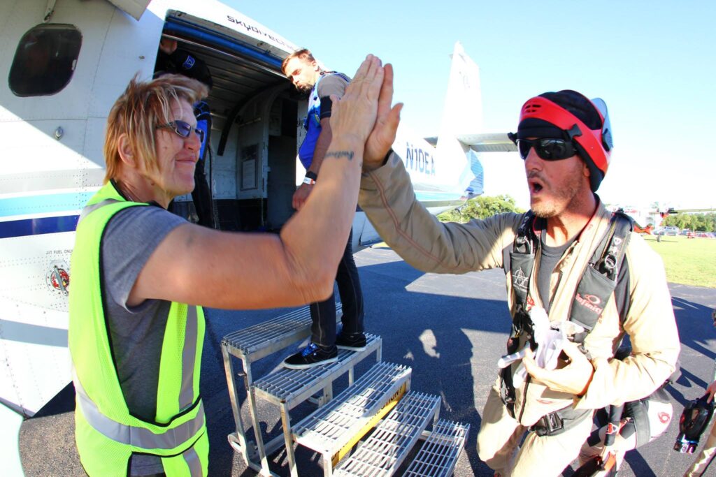 Loader, Christa Cross high fives a skydiver as they board the plane at Skydive Chicago